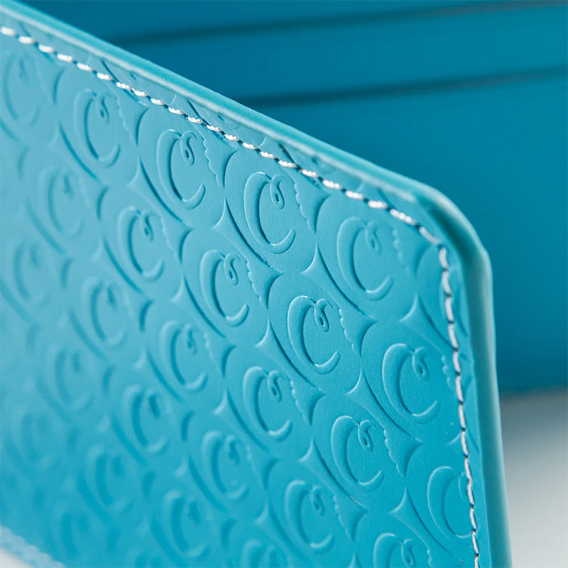 Urban Chic embossed wallet in blue on a wooden table, emphasizing its modern aesthetic.